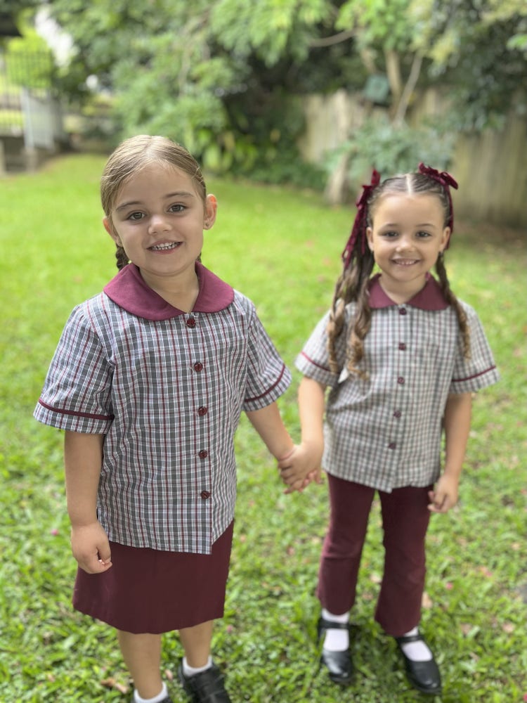 An image of two students standing in a grassed area holding hands and smiling