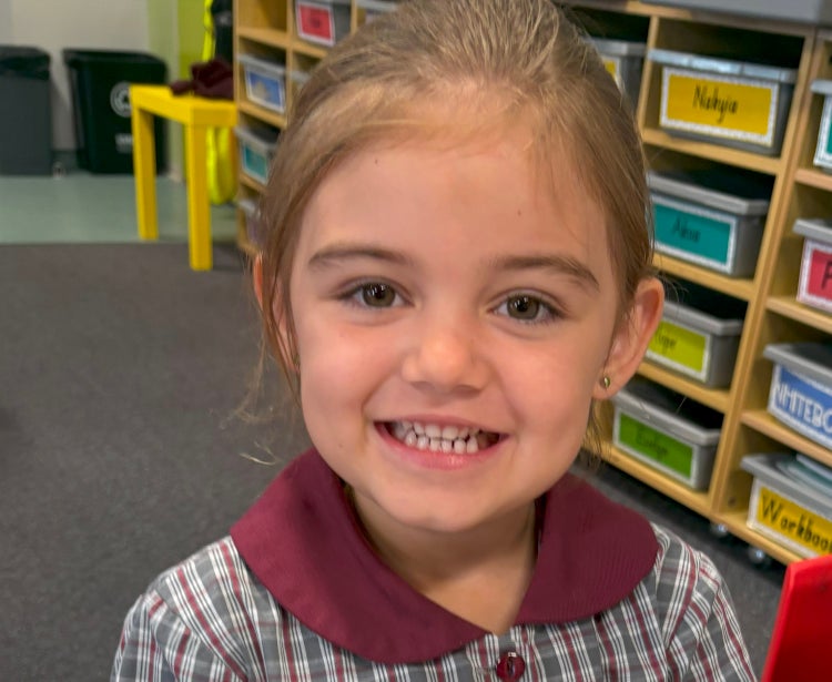 A close up image of a young girl in uniform smiling at the camera