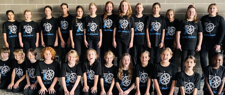 A photo of a group of choir students standing in and sitting in two rows all wearing black shirts