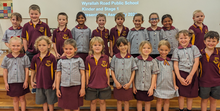 An image of a group of students standing in two rows on the stage in the school hall
