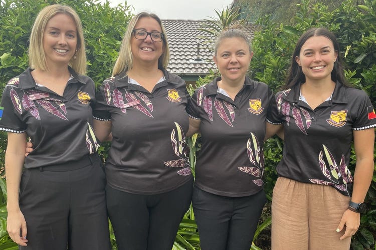 An image of four teachers standing in a row wearing their staff shirts
